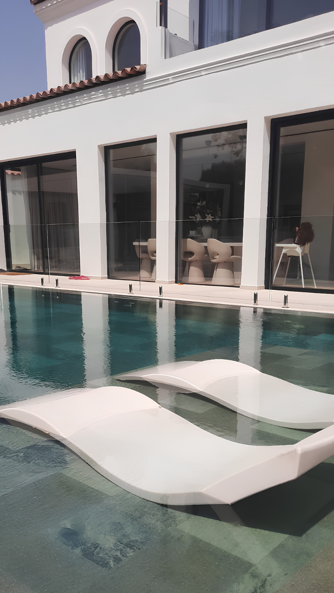 Frameless glass pool fence set against a white Dubai villa
