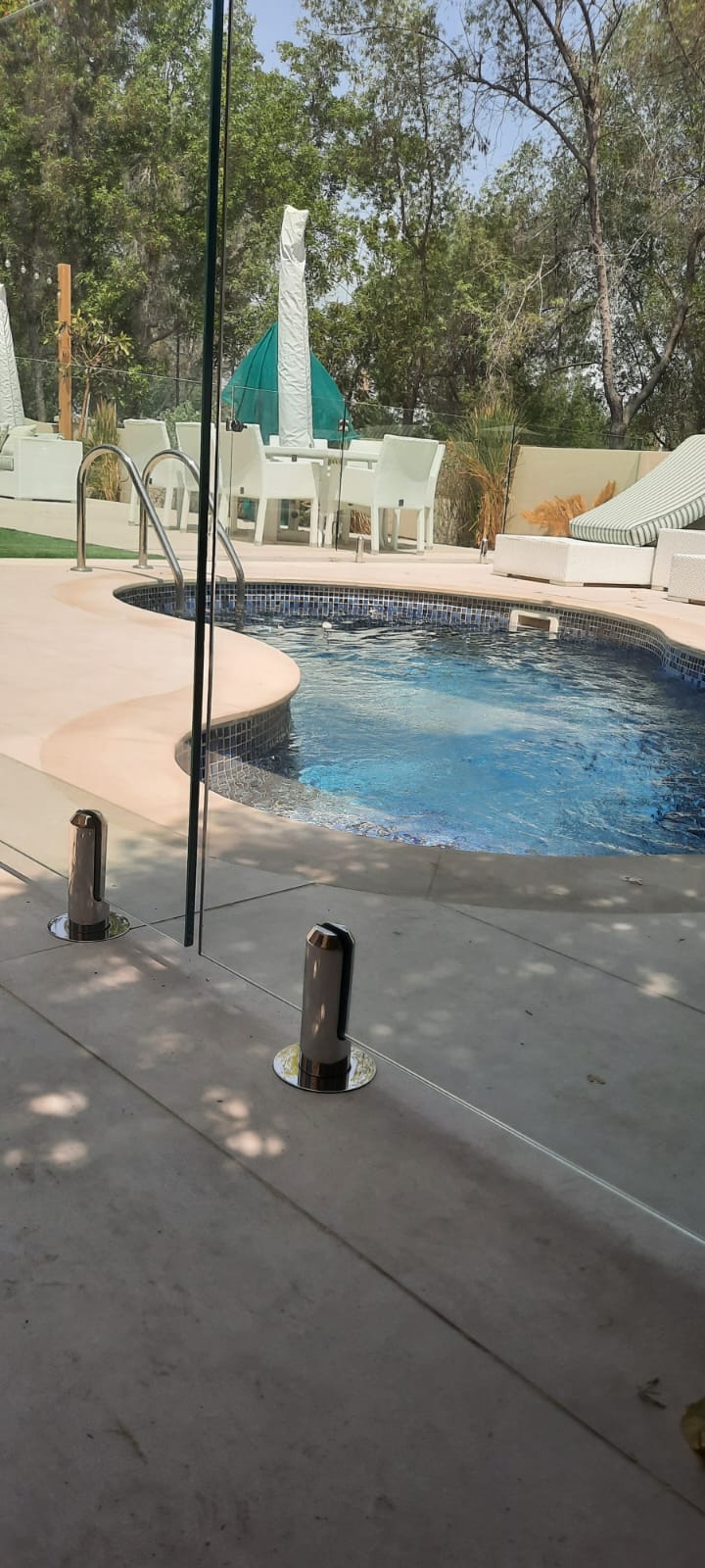 Frameless glass pool fence around a villa pool with garden seating