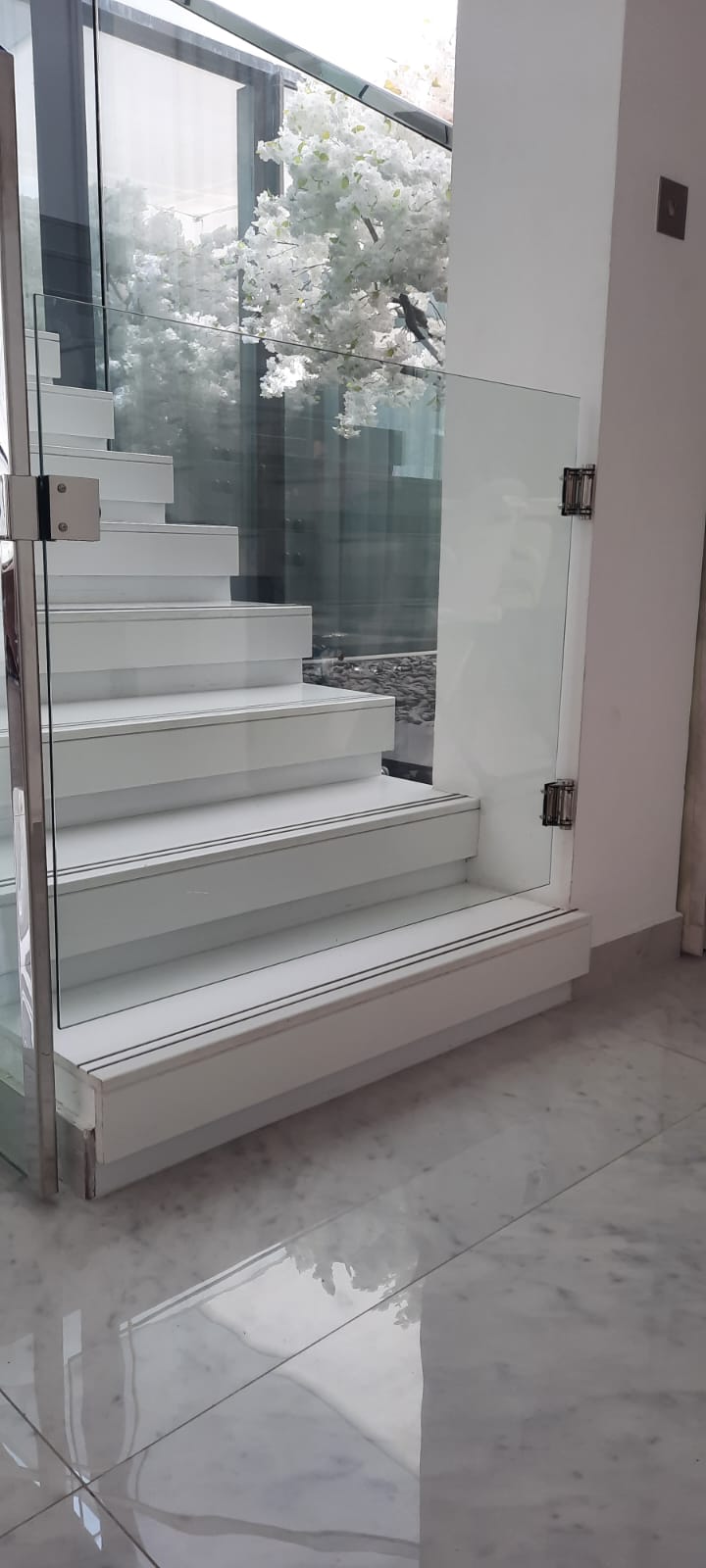 Frameless glass stair balustrade with marble steps and white finishes