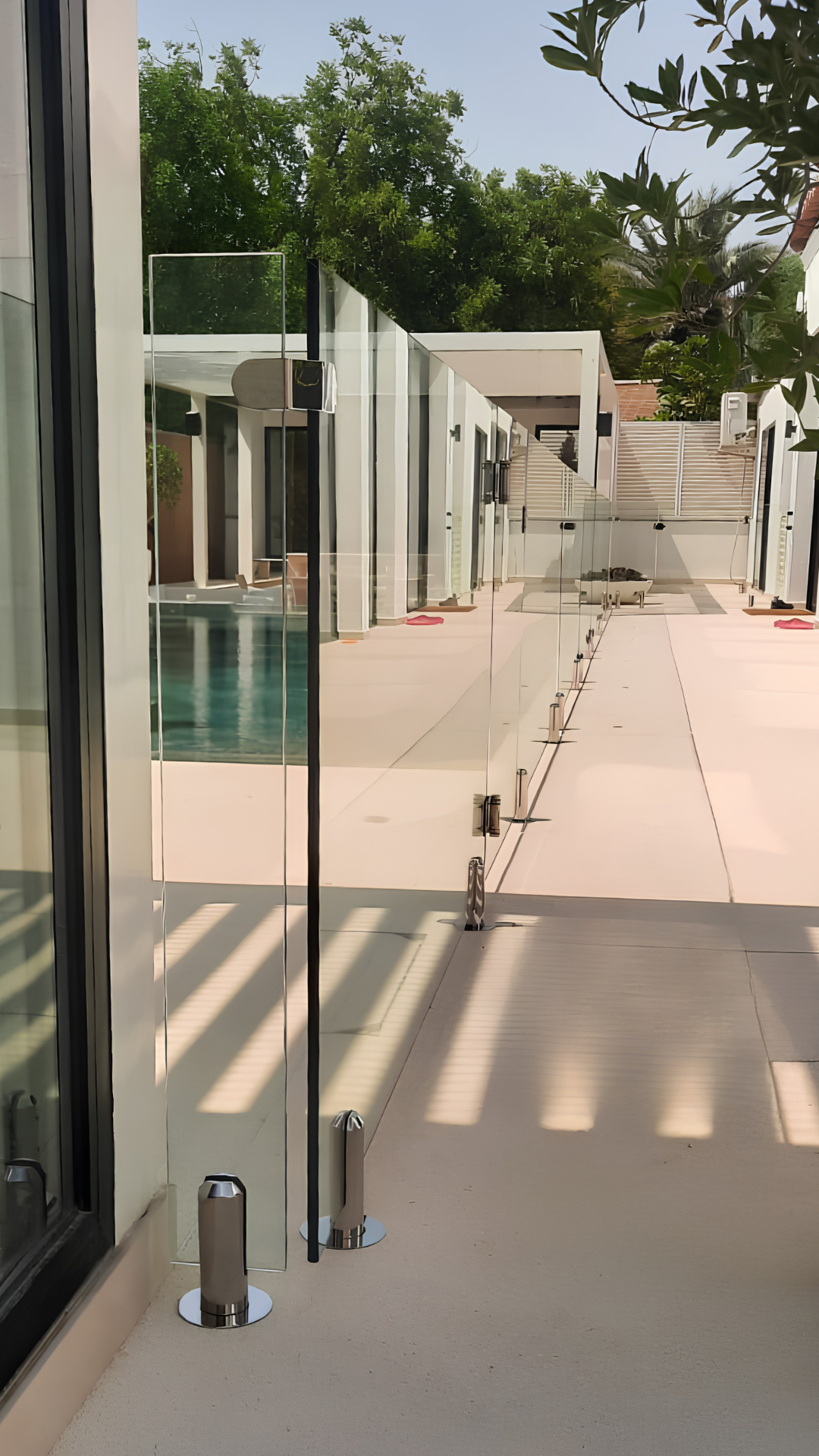 Custom frameless glass pool gate installed along a villa terrace